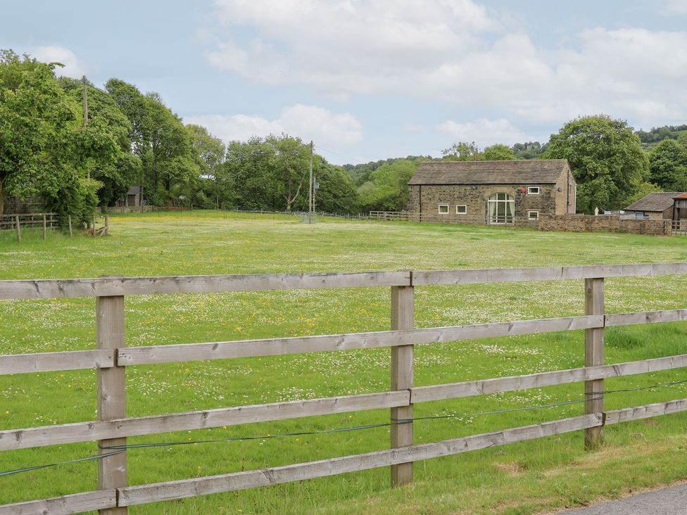 A stone building with a grassy field and fence at Bullace Barn Millhouse Green