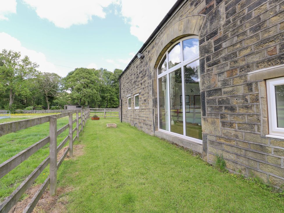An outdoor area showing the stone wall and windows of Bullace Barn in Millhouse Green