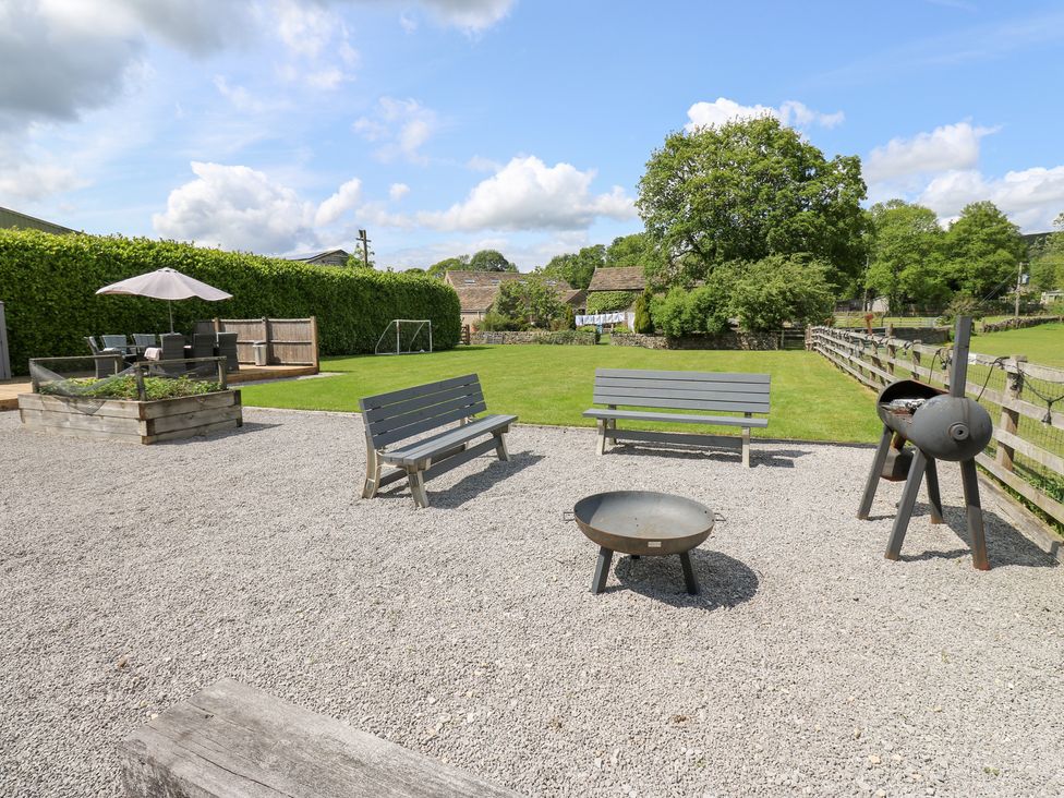 A garden with benches, fire pit and grill at Bullace Barn in Millhouse Green