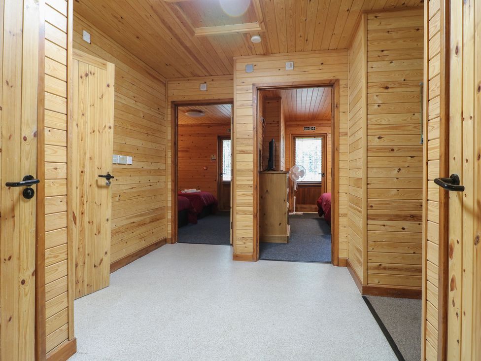 A wooden hallway with multiple doorways leading to bedrooms at Birch Lodge in Rosliston