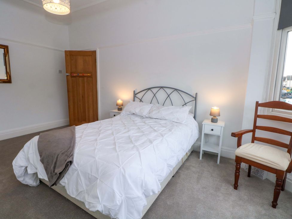 A bedroom with a bed, table, lamp, and chair at Thomas Lane in Liverpool