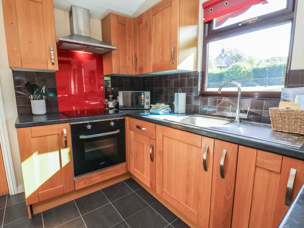 A kitchen with wooden cabinets and appliances at Bluebell Lodge, Saltburn-by-the-Sea