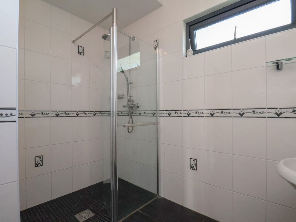 A bathroom with a shower and tiled walls at Bluebell Lodge in Saltburn-by-the-Sea