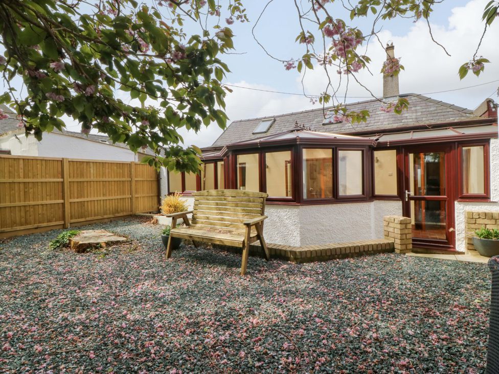 A garden with a wooden bench and gravel at Ty Taid in Llanddaniel Fab near Beaumaris