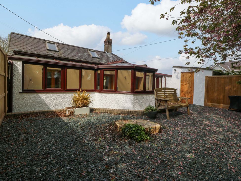 A garden with a wooden bench and gravel at Ty Taid in Llanddaniel Fab near Beaumaris