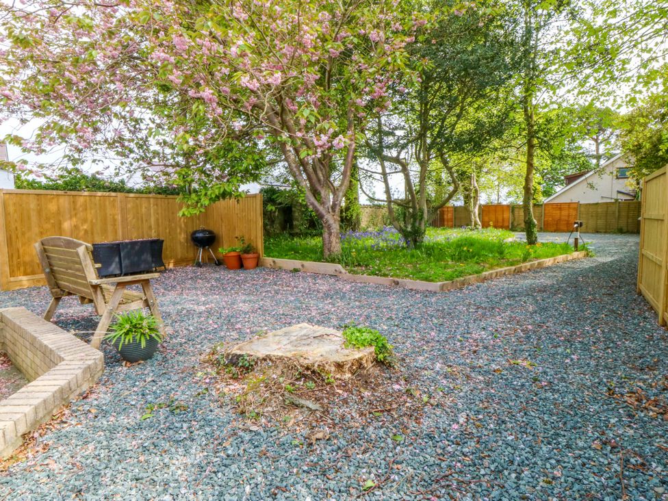 A garden with a bench, grill, and planters at Ty Taid in Llanddaniel Fab near Beaumaris
