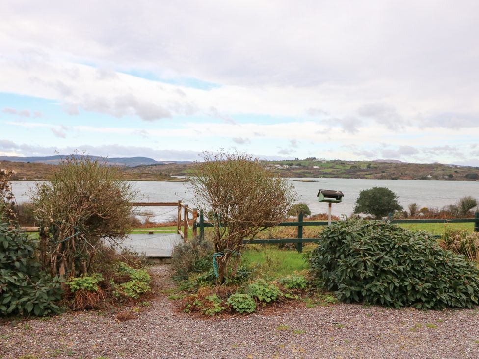 A view of a lake with shrubs and a fence at Herons Cove Cottage Ballydehop