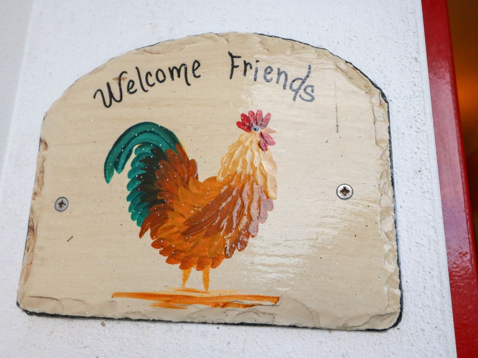 A welcome sign with a rooster design at Herons Cove Cottage in Ballydehop