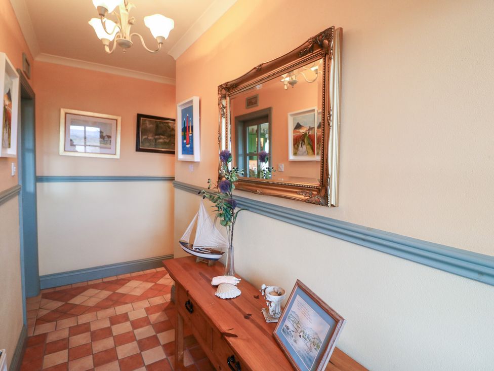 A hallway with a mirror and wall art at Herons Cove Cottage Ballydehop