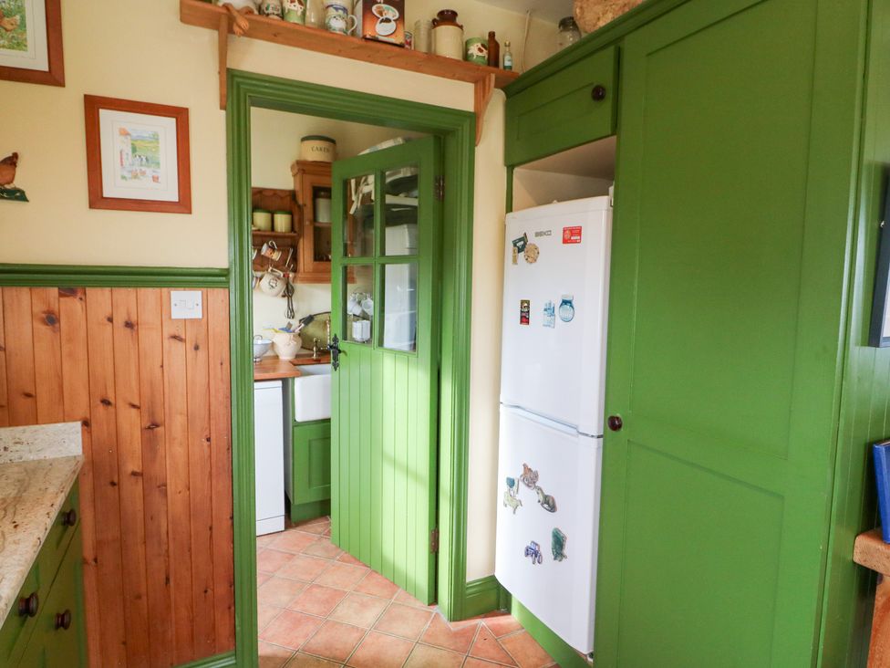 A kitchen with a fridge and cabinets at Herons Cove Cottage in Ballydehop