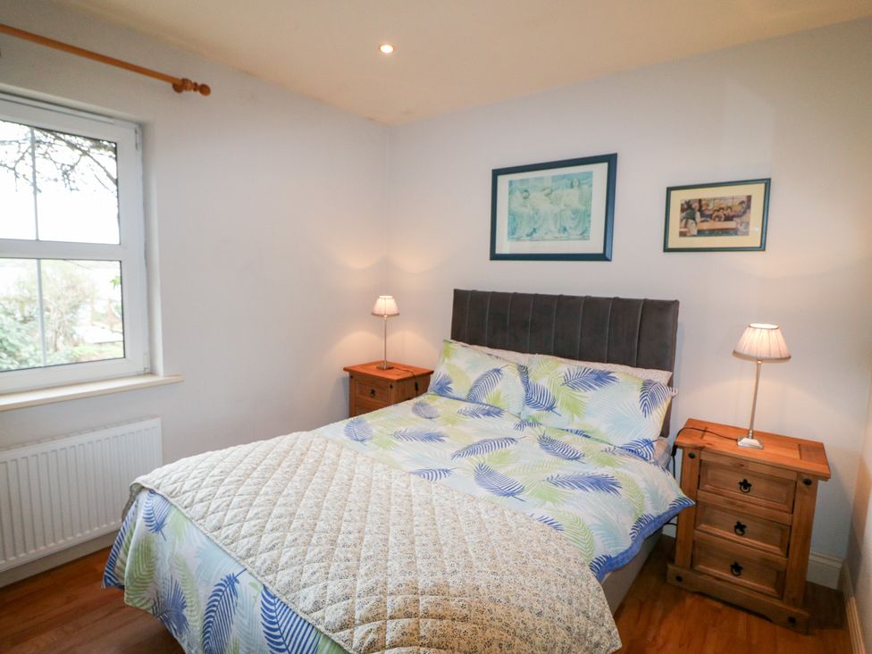 A bedroom with a bed and bedside tables at Herons Cove Cottage Ballydehop