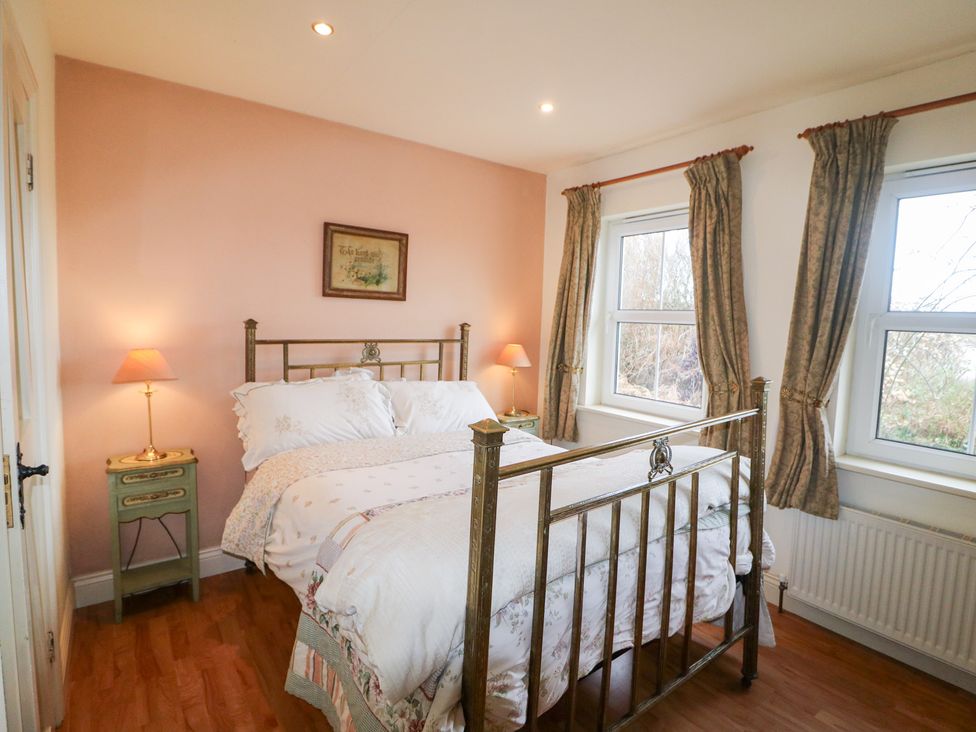 A bedroom with a bed and nightstand at Herons Cove Cottage Ballydehop