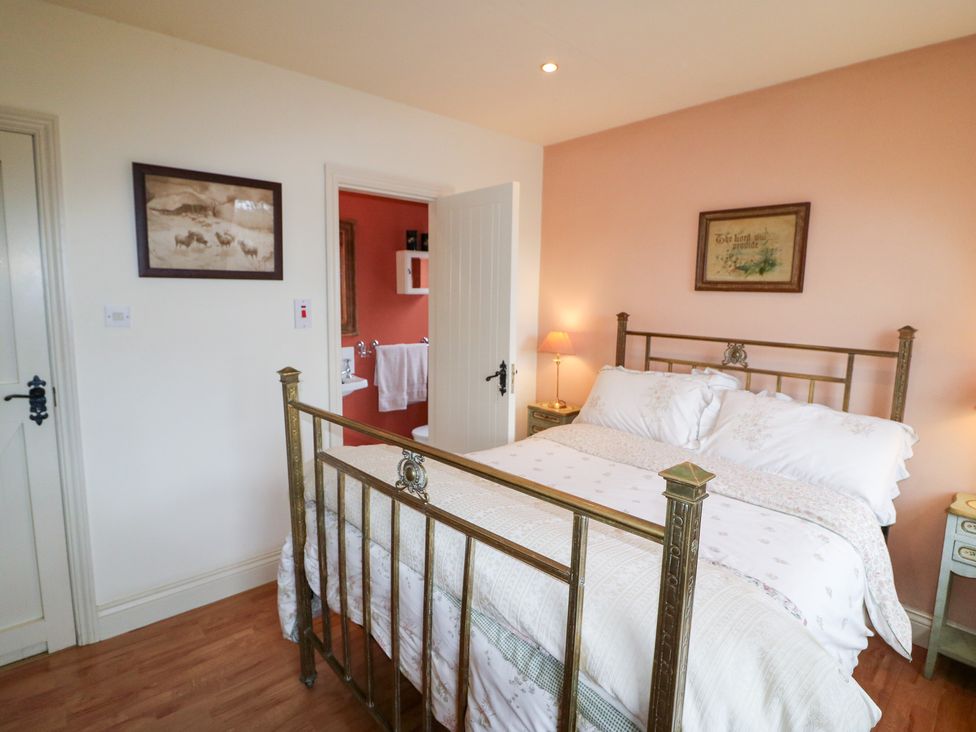 A bedroom with a bed and a lamp at Herons Cove Cottage Ballydehop