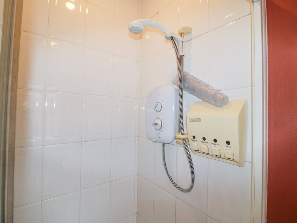 A shower area with a showerhead and control unit at Herons Cove Cottage Ballydehop
