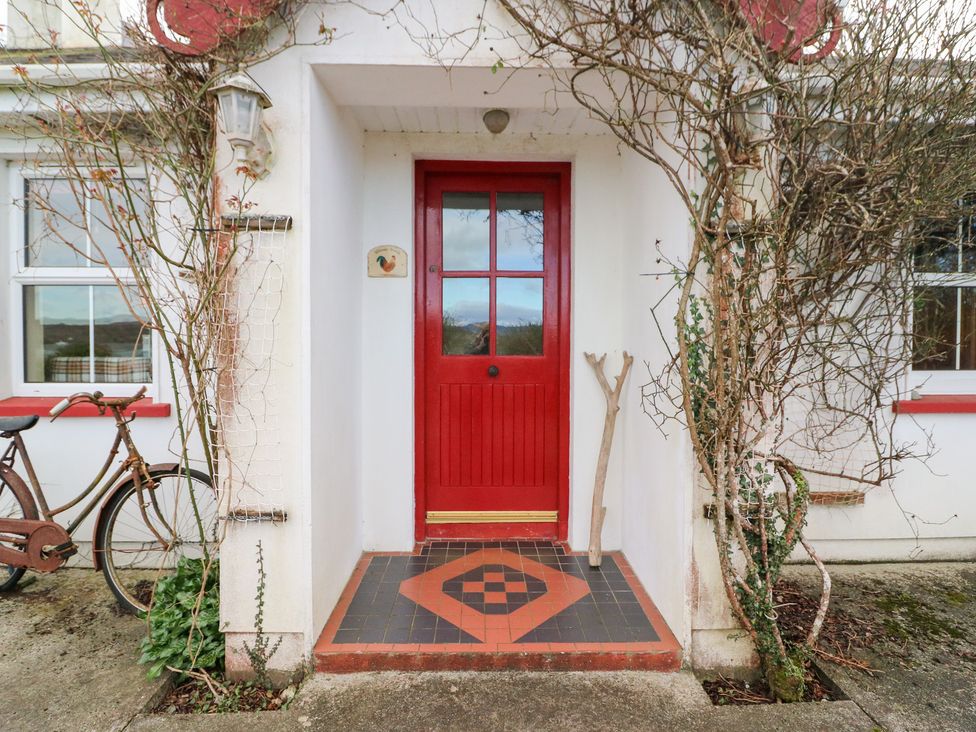 A front entrance with a red door and bicycle at Herons Cove Cottage Ballydehop