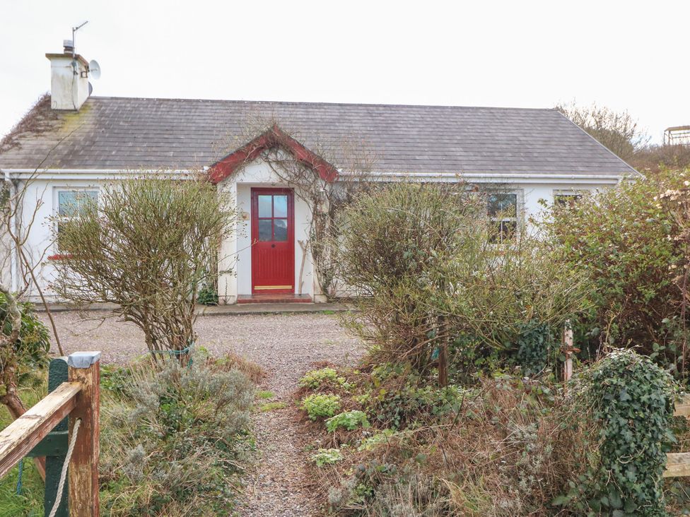 A house with a red door and garden at Herons Cove Cottage, Ballydehop