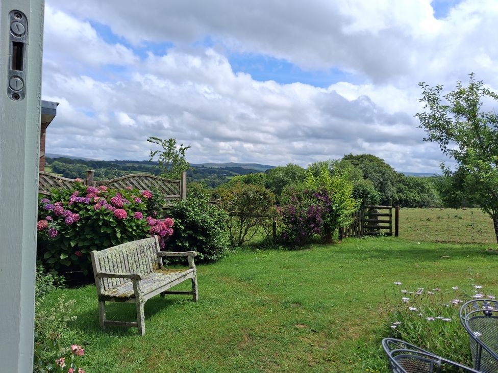 A garden with a bench and flowers at Woodstone Barn near Whitchurch near Tavistock