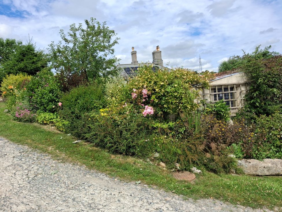 A garden with flowers and a house at Woodstone Barn in Whitchurch near Tavistock