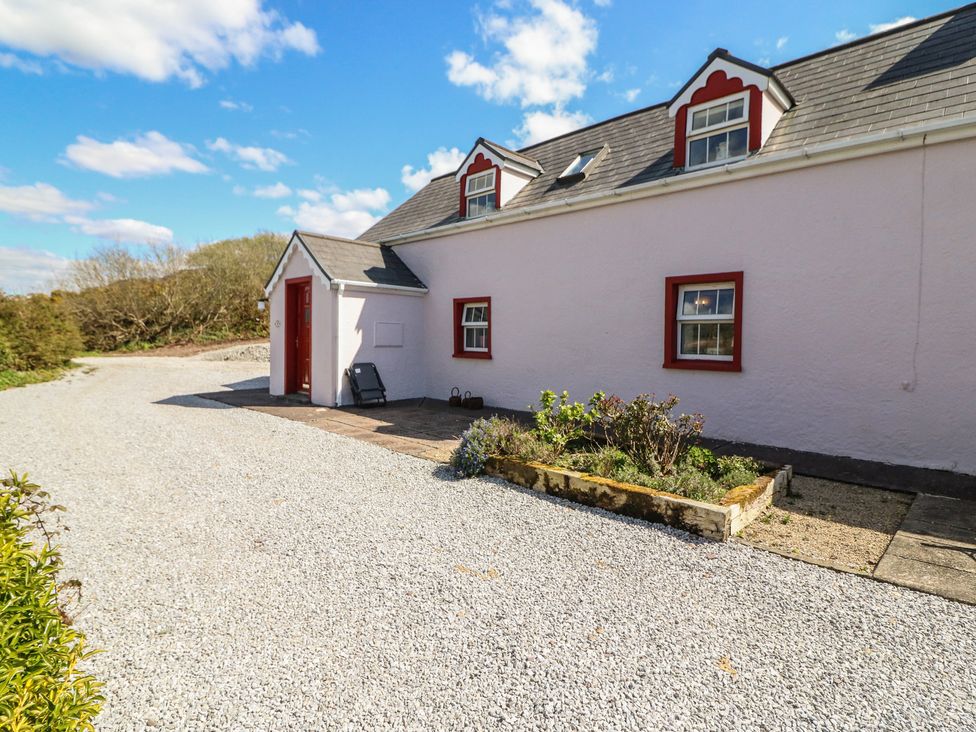 A cottage with a gravel pathway and garden at Fuschia Cottage, Waterville, County Kerry