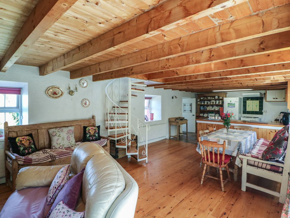 A living room with a sofa, table, and staircase at Fuschia Cottage, Waterville, County Kerry
