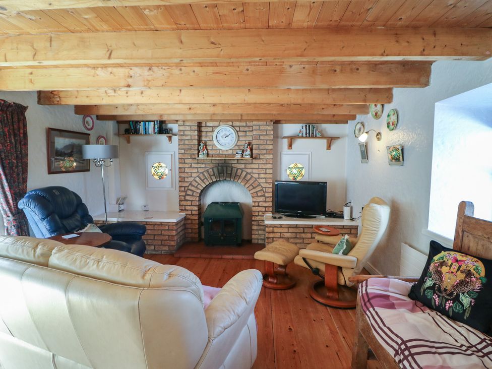 A living room with a fireplace and television at Fuschia Cottage, Waterville, County Kerry