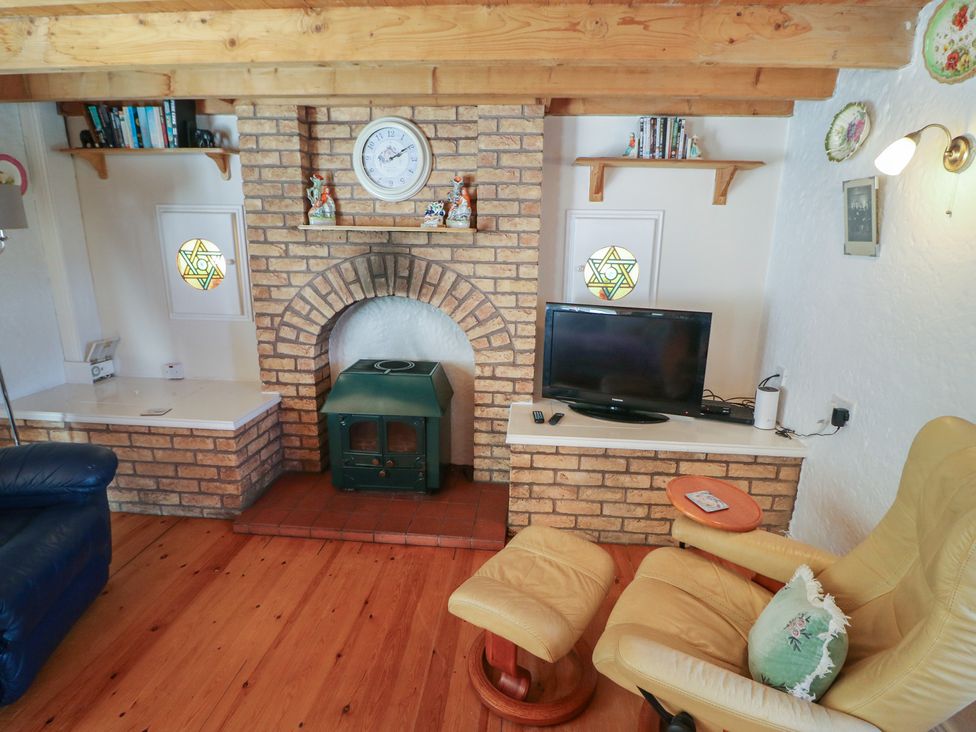 A living room with a fireplace and television at Fuschia Cottage in Waterville, County Kerry