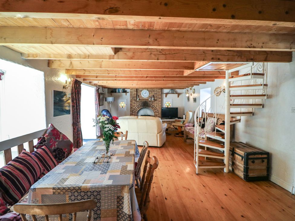 A living room with a dining table and sofa at Fuschia Cottage in Waterville, County Kerry