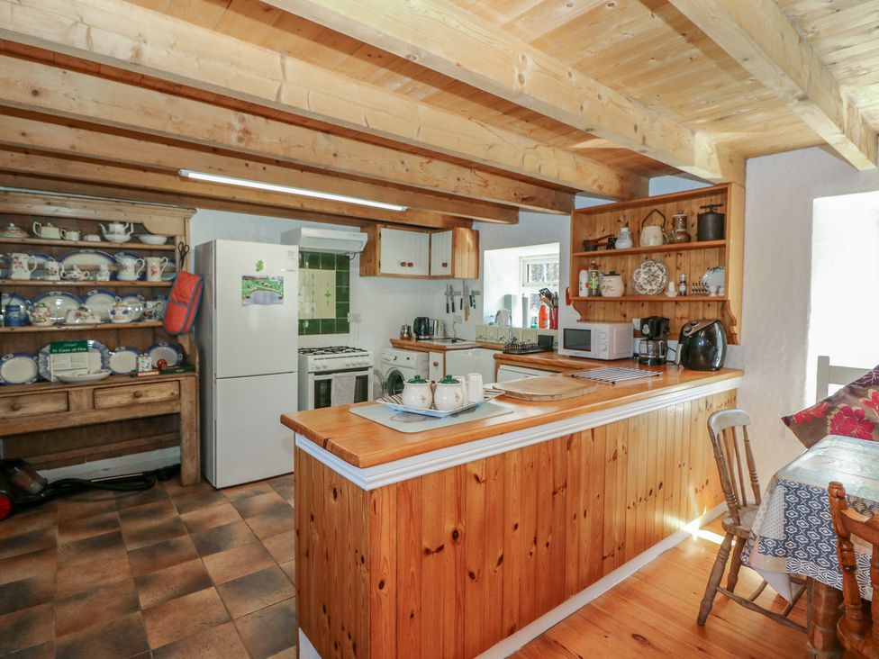 A kitchen with a refrigerator, oven, sink and dining table at Fuschia Cottage, Waterville, County Kerry