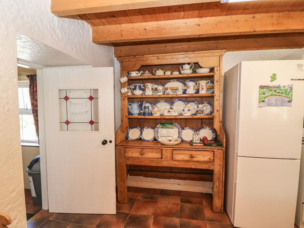 A kitchen with a wooden shelf displaying dishes at Fuschia Cottage Waterville, County Kerry