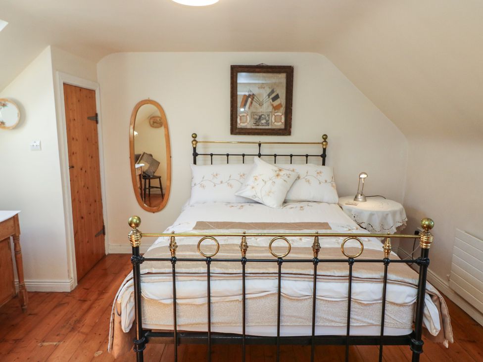 A bedroom with a bed and a table with a lamp at Fuschia Cottage, Waterville, County Kerry