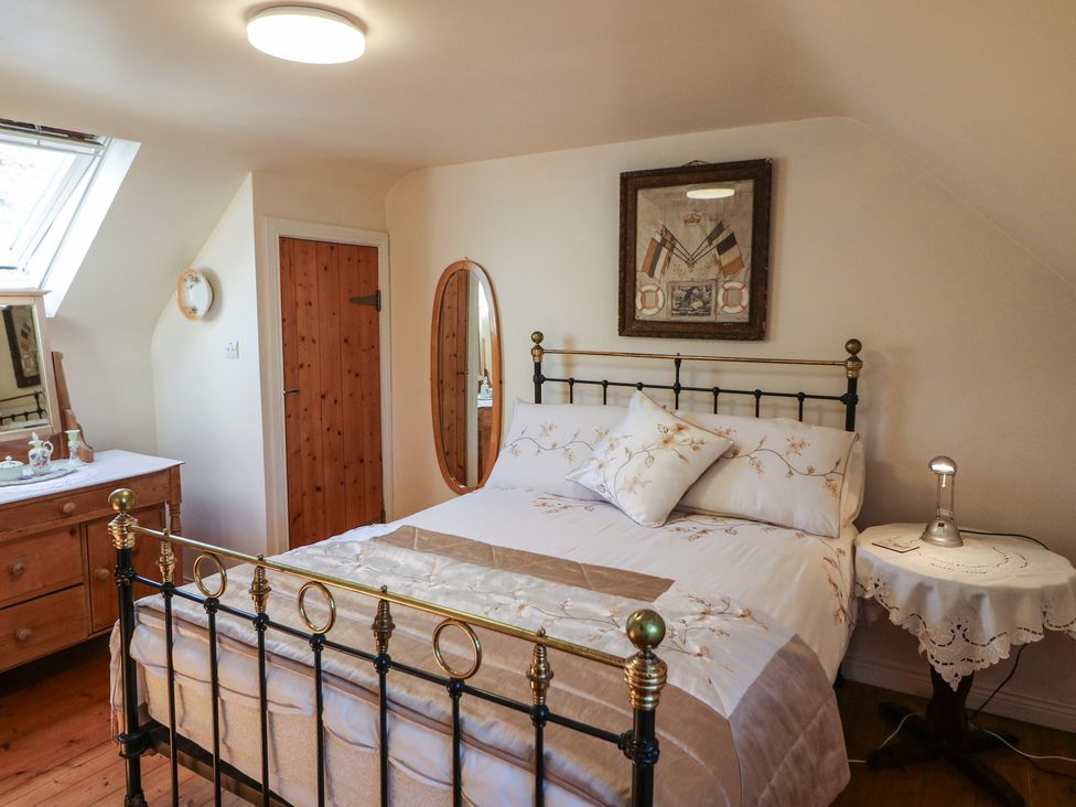A bedroom with a bed, bedside table and mirror at Fuschia Cottage Waterville, County Kerry