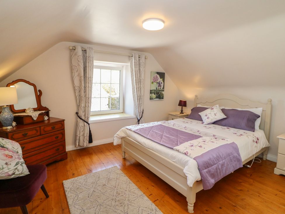 A bedroom with a bed, dresser, and window at Fuschia Cottage, Waterville, County Kerry