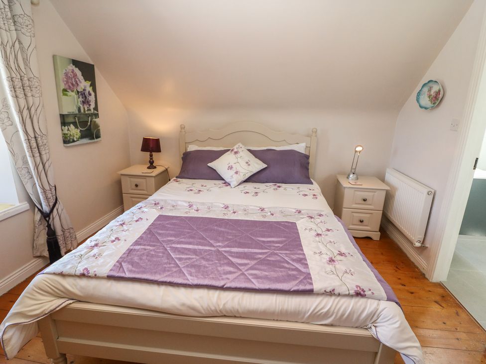 A bedroom with a bed and bedside table at Fuschia Cottage in Waterville, County Kerry