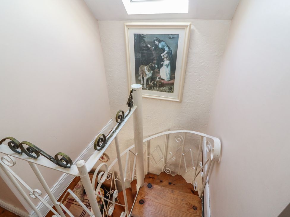 A staircase with a painting and wooden floor at Fuschia Cottage in Waterville, County Kerry