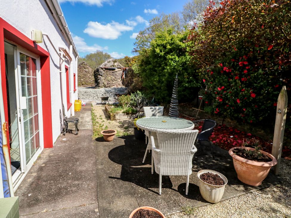 A garden with a table and chairs and planters at Fuschia Cottage in Waterville, County Kerry