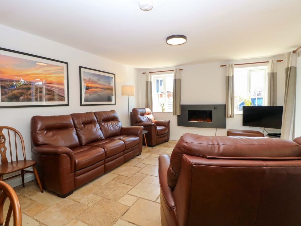 A living room with sofas, a fireplace, and a television at Mill Lodge in Brisley