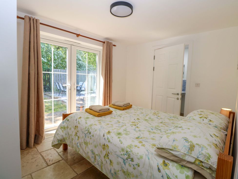A bedroom with a bed and patio doors at Mill Lodge in Brisley