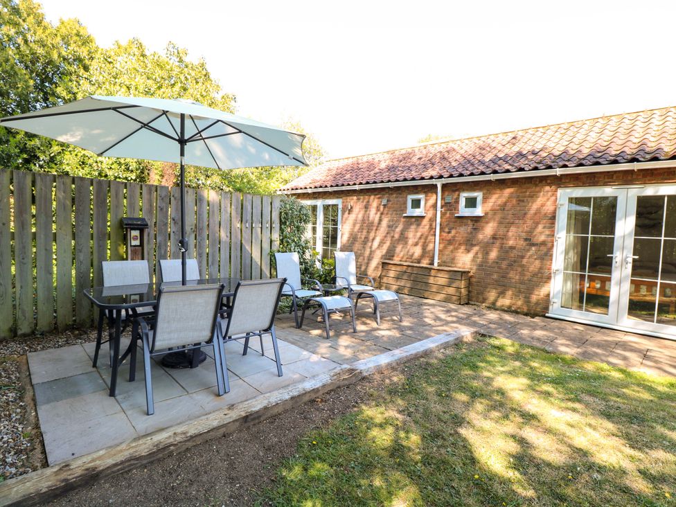 An outdoor seating area with a table and chairs at Mill Lodge in Brisley