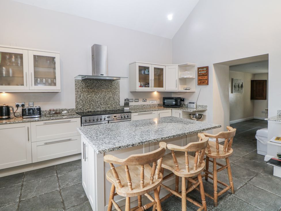 A kitchen with an island and stools at The Old Robin Hood in Holmesfield near Bakewell