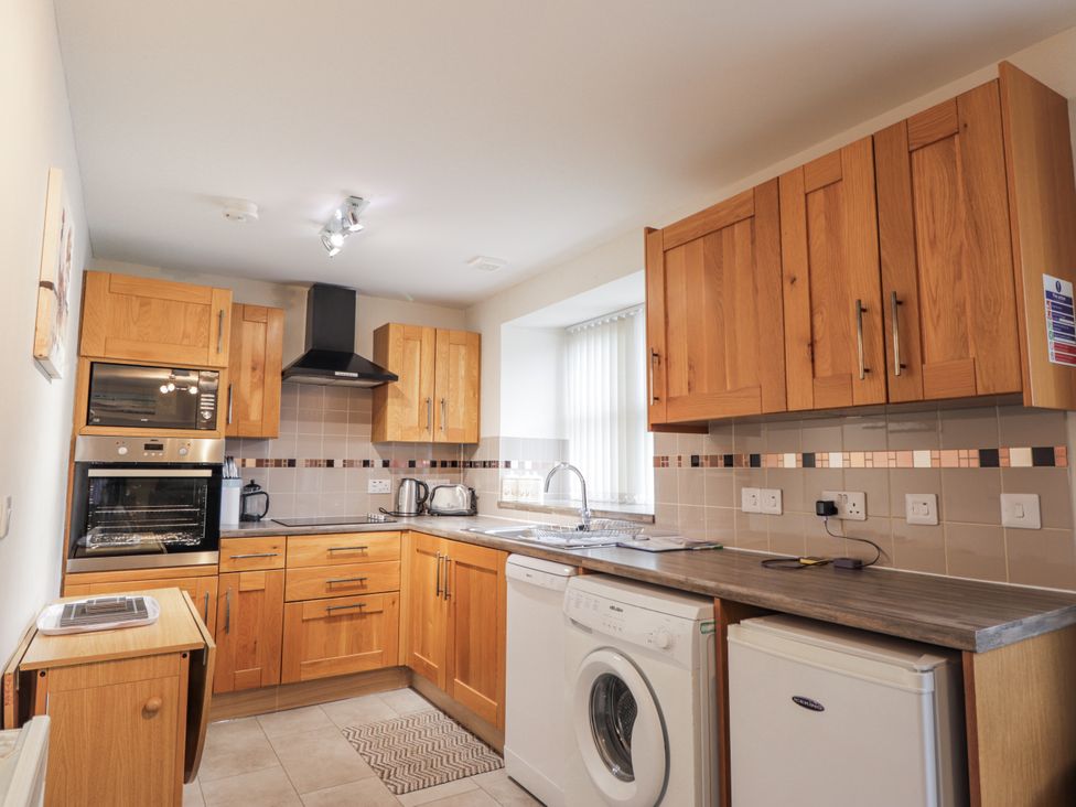 A kitchen with wooden cabinets and appliances at The Croft House in Muir of Ord near Beauly