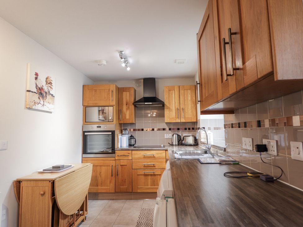 A kitchen with appliances and wooden cabinets at The Croft House in Muir of Ord near Beauly