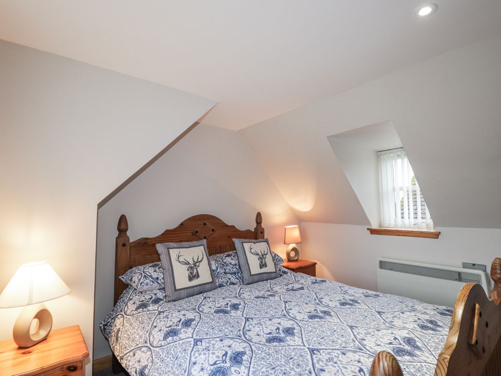 A bedroom with a bed and lamp at The Croft House in Muir of Ord near Beauly