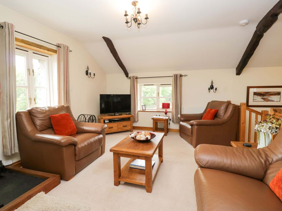 A living room with leather sofas and a coffee table at Copper Beech Cottage in Torver