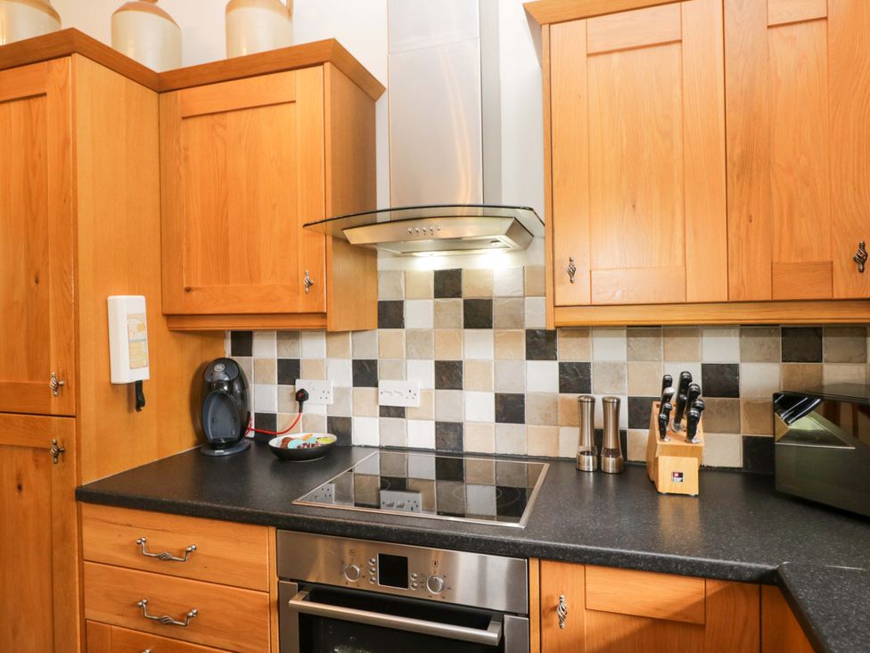 A kitchen with wooden cabinets and an electric stove at Copper Beech Cottage in Torver
