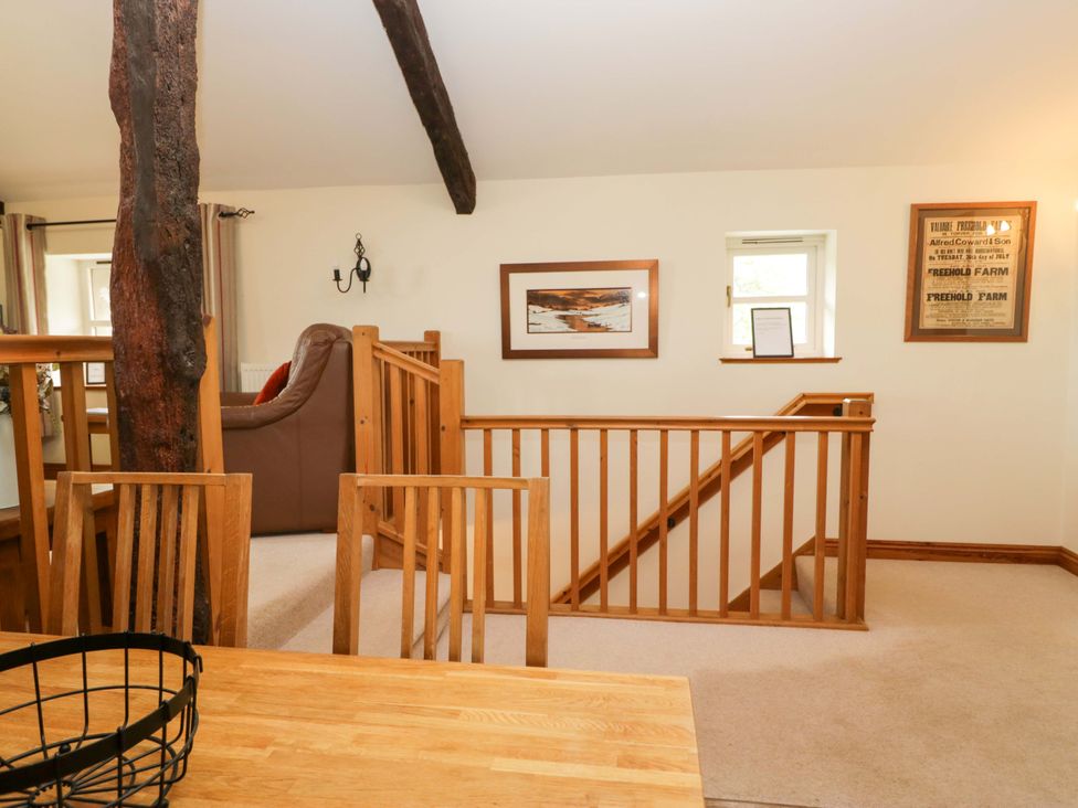 A living room with a sofa and staircase at Copper Beech Cottage in Torver