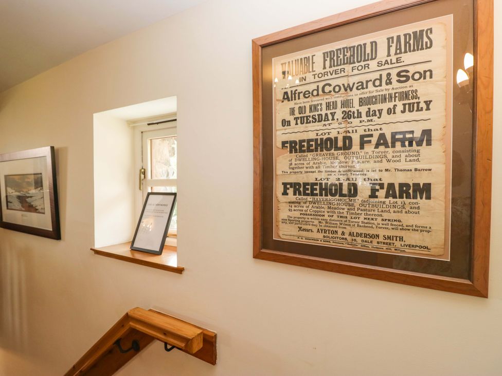 A framed poster and window in a hallway at Copper Beech Cottage in Torver