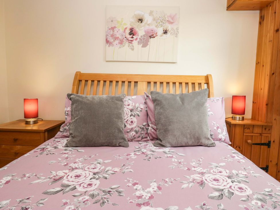 A bedroom with a bed and lamps at Copper Beech Cottage in Torver