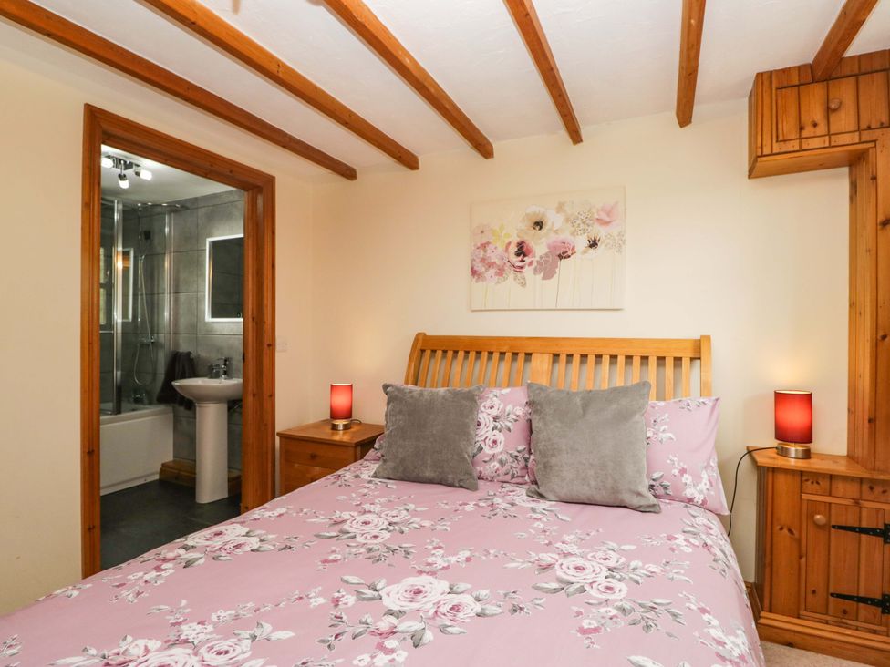 A bedroom with a bed and bathroom access at Copper Beech Cottage in Torver