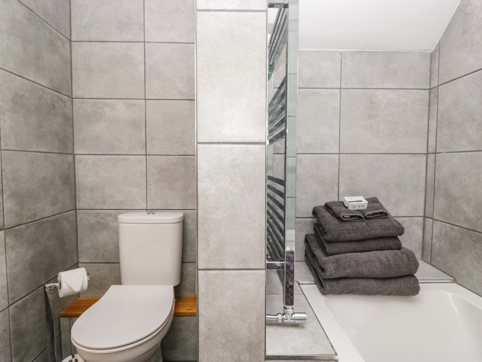 A bathroom with a toilet and towels on a rack at Copper Beech Cottage in Torver