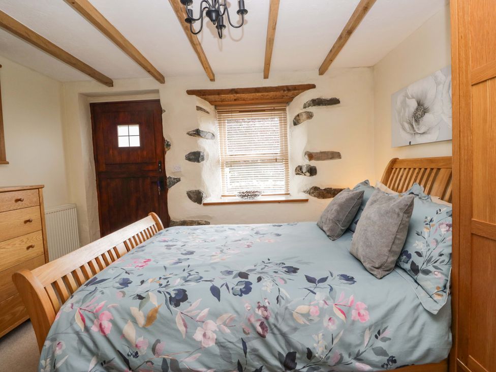 A bedroom with a bed and dresser at Copper Beech Cottage in Torver
